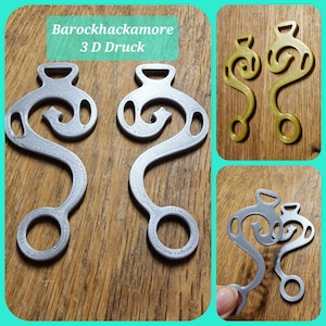 Op de afbeelding: Twee zilveren 3D-geprinte haken met een decoratief ontwerp. De haken zijn S-vormig met een kleine lus bovenaan en een grotere lus onderaan. De tekst "Barockhackamore 3D Druck" is zichtbaar op de achtergrond.