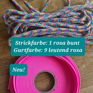 Pu&ograve; includere: Una corda rosa e verde con il testo "Strickfarbe: 1 rosa bunt Gurtfarbe: 9 leutend rosa Neu!" e un cinturino rosa.