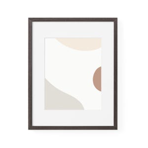May include: A framed abstract art print with a minimalist design in neutral tones. The artwork features beige, taupe, and brown organic shapes on a white background. The dark brown frame provides a contrasting border.