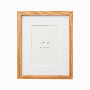May include: A rectangular wooden picture frame with a white mat. The frame is light brown and has a visible wood grain. The mat opening is 6" x 8", and the overall frame size is 9" x 12".