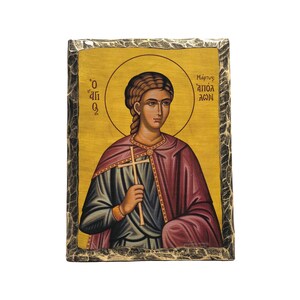 May include: A hand-painted icon of a saint holding a cross. The icon is on a wooden panel with a gold-colored frame. The saint is wearing a blue and purple robe and has a halo around their head. The text on the icon reads "Martyr Saint" in Greek.