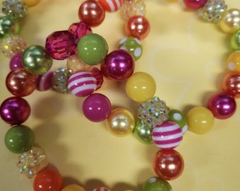 May include: Two colorful beaded bracelets with a mix of pink, green, yellow, orange, and white beads. The bracelets feature striped and polka dot patterns.