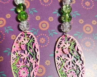 May include: A pair of dangle earrings with pink and green floral designs. The earrings feature a silver hook and a chain of clear and green beads.
