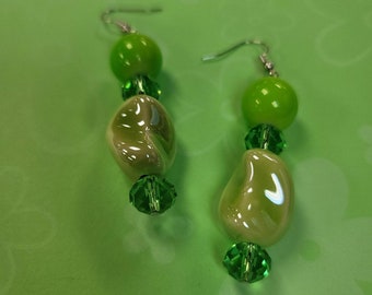 May include: A pair of green and white dangle earrings with green glass beads and silver hooks.