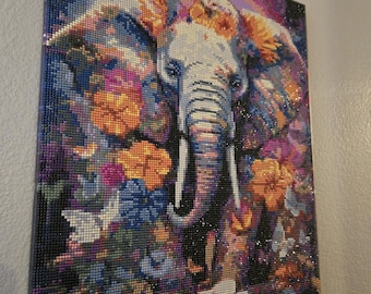 May include: A rectangular diamond painting wall art piece featuring a central elephant head surrounded by vibrant, multi-colored flowers in shades of orange, pink, blue, and purple. The image is composed of small, reflective, faceted beads.