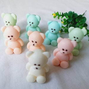 May include: A collection of seven small teddy bear figurines in various pastel colors, including light blue, pink, and white. The bears are all sitting upright with their paws in front of them.