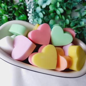 May include: A bowl filled with heart-shaped soaps in various pastel colours, including pink, yellow, green, and white.