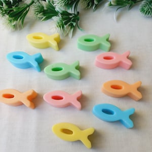 Op de afbeelding: Negen pastelkleurige, visvormige zeepjes. De zeepjes zijn in tinten geel, blauw, groen, roze en oranje.