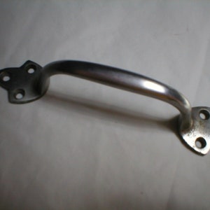 May include: A silver metal door handle with a curved design and four holes on each end. The handle has a smooth, polished finish.