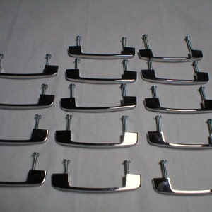 May include: A set of twelve chrome-finished cabinet handles. Each handle is rectangular with a curved grip and includes two screws for mounting. The handles are arranged in a grid pattern against a white background.