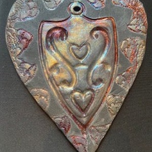 A heart embossed shape pressed into a Raku clay piece, bisque fired, then raku glazed fired outside in raku kiln. copper, gold colors image 1