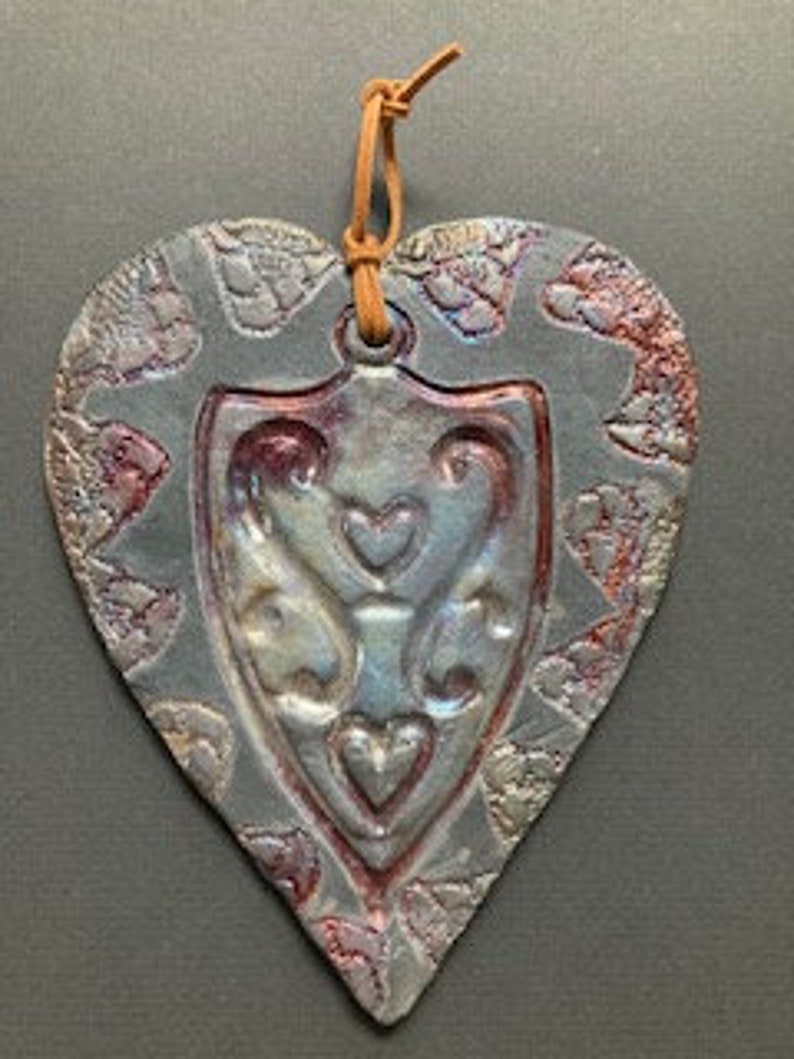A heart embossed shape pressed into a Raku clay piece, bisque fired, then raku glazed fired outside in raku kiln. copper, gold colors image 3