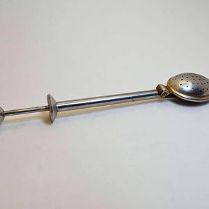 Può includere: Infusore per tè in acciaio inossidabile con una testa perforata di forma ovale e un lungo manico. Il manico ha un'impugnatura a forma di disco e un'estremità piccola e rotonda. L'infusore è progettato per foglie di tè sfuse.