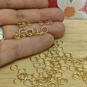 May include: A large pile of gold jump rings. The rings are small and round, and they are ideal for jewellery making.