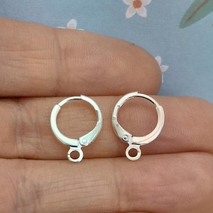 May include: Two silver earring hoops with a jump ring closure. The hoops are approximately 2.5 cm in diameter.