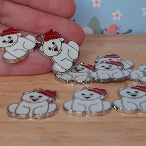 May include: A set of ten silver charm pendants featuring polar bears wearing red Santa hats. The bears are white with black eyes and noses. The charms are perfect for adding a festive touch to jewellery or crafts.