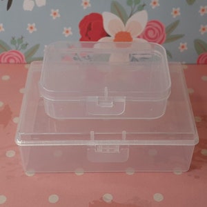 May include: Two clear plastic storage boxes with lids. The smaller box is stacked inside the larger box.