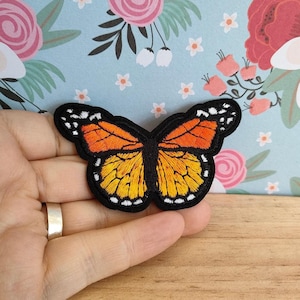 May include: Orange and black embroidered butterfly patch with white accents.