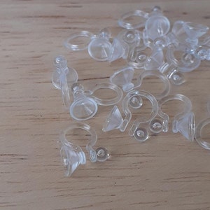 May include: A group of clear plastic earring backs with a small loop and a suction cup on the back.