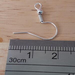 Puede incluir: Gancho para pendientes de plata con una peque&ntilde;a bola en la parte superior, que mide aproximadamente 2,5 cm de largo. El gancho se muestra junto a una regla.