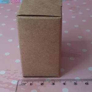 K&ouml;nnte beinhalten: Eine braune Pappbox mit einem Lineal, das 7,6 cm lang ist.
