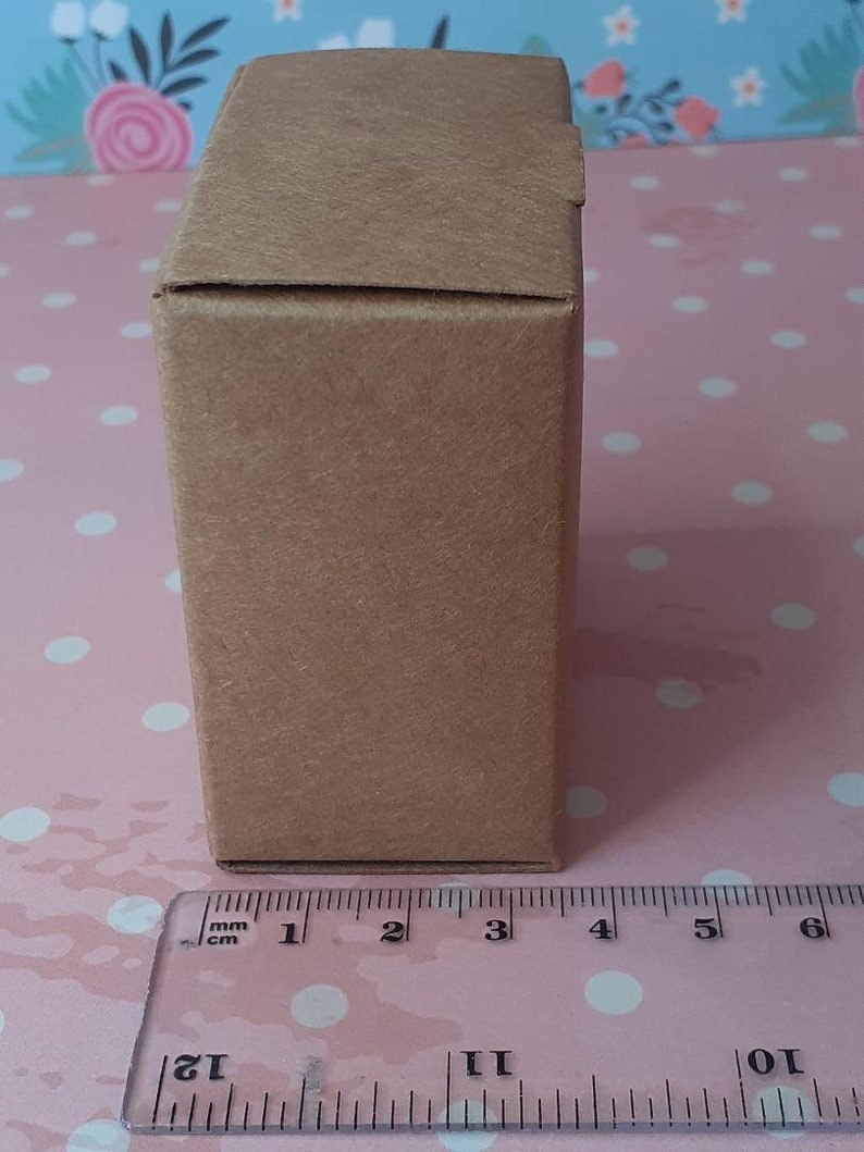 K&ouml;nnte beinhalten: Eine braune Pappbox mit einem Lineal, das 7,6 cm lang ist.