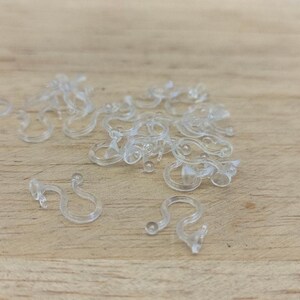 May include: A pile of clear plastic hooks, likely used for hanging items such as Christmas lights or other decorations.