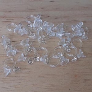 May include: A pile of clear plastic earring backs with a small, clear, cone-shaped piece on the end of each back.