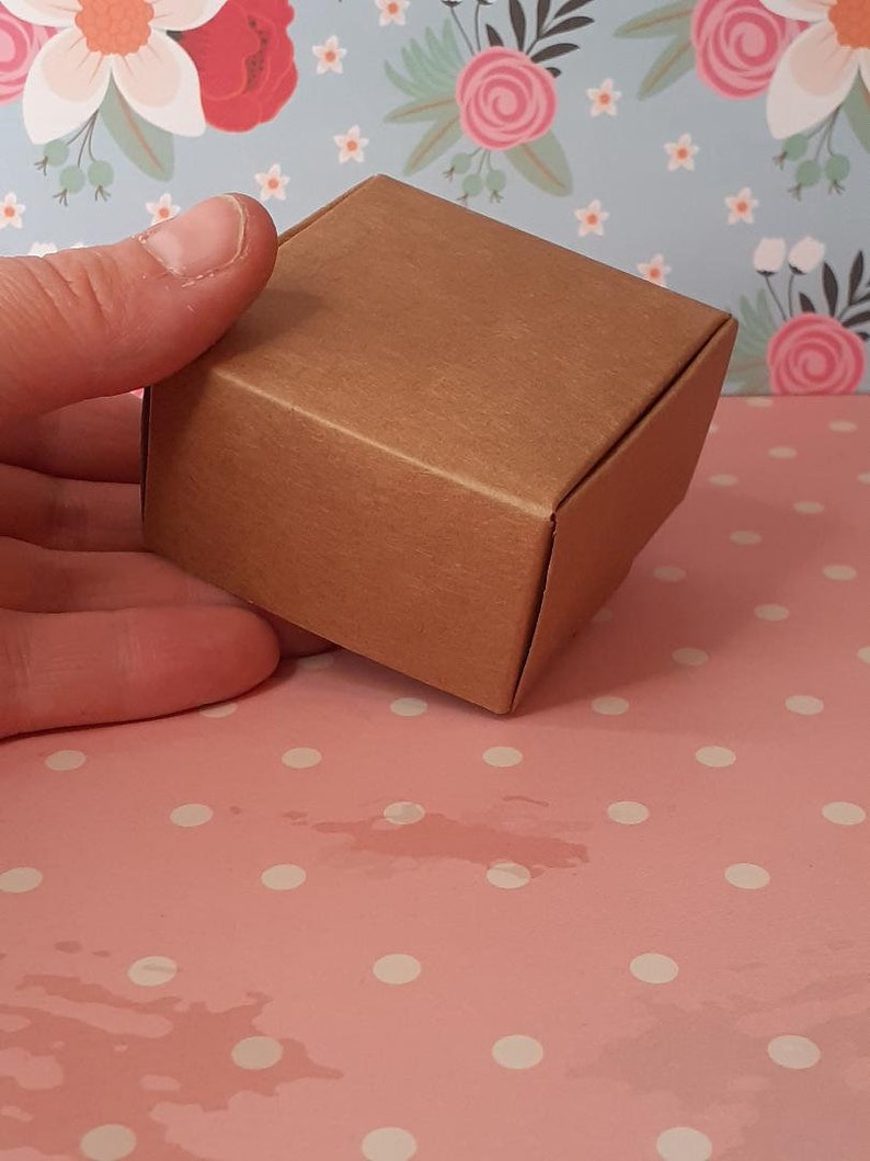 K&ouml;nnte beinhalten: Eine kleine braune Schachtel aus Pappe mit einer strukturierten Oberfl&auml;che. Die Schachtel ist leer und bereit, mit einem Geschenk oder anderen kleinen Gegenst&auml;nden gef&uuml;llt zu werden.