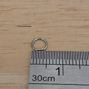 May include: A silver jump ring measuring 1 cm in diameter, next to a ruler.