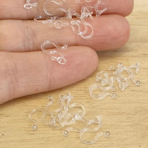May include: A pile of clear plastic earring backs. The backs are designed to hold earrings in place and are commonly used with stud earrings.