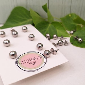 May include: A close-up of a set of silver ball stud earrings on a white card with the text "littlejems.uk".