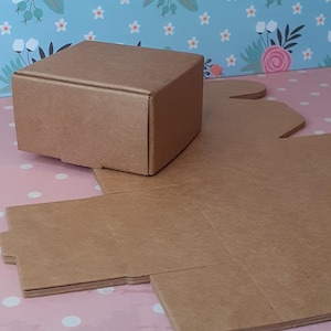K&ouml;nnte beinhalten: Ein brauner Karton mit Deckel. Die Schachtel ist flach zusammengefaltet und bereit zum Zusammenbauen. Die Schachtel ist aus robustem Karton und eignet sich perfekt zum Verpacken kleiner Geschenke oder Artikel.