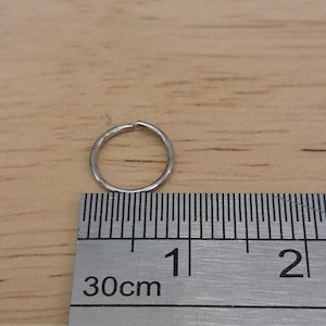 May include: A silver ring measuring 1 inch in diameter, shown next to a ruler.