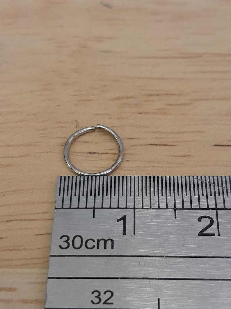 May include: A silver ring measuring 1 inch in diameter, shown next to a ruler.