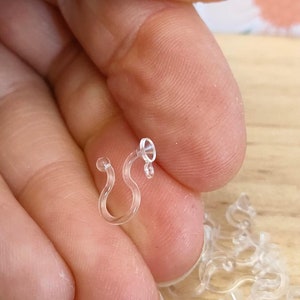 May include: Close-up of a clear plastic hook, a common type of hook used for hanging items like Christmas lights or other decorations.
