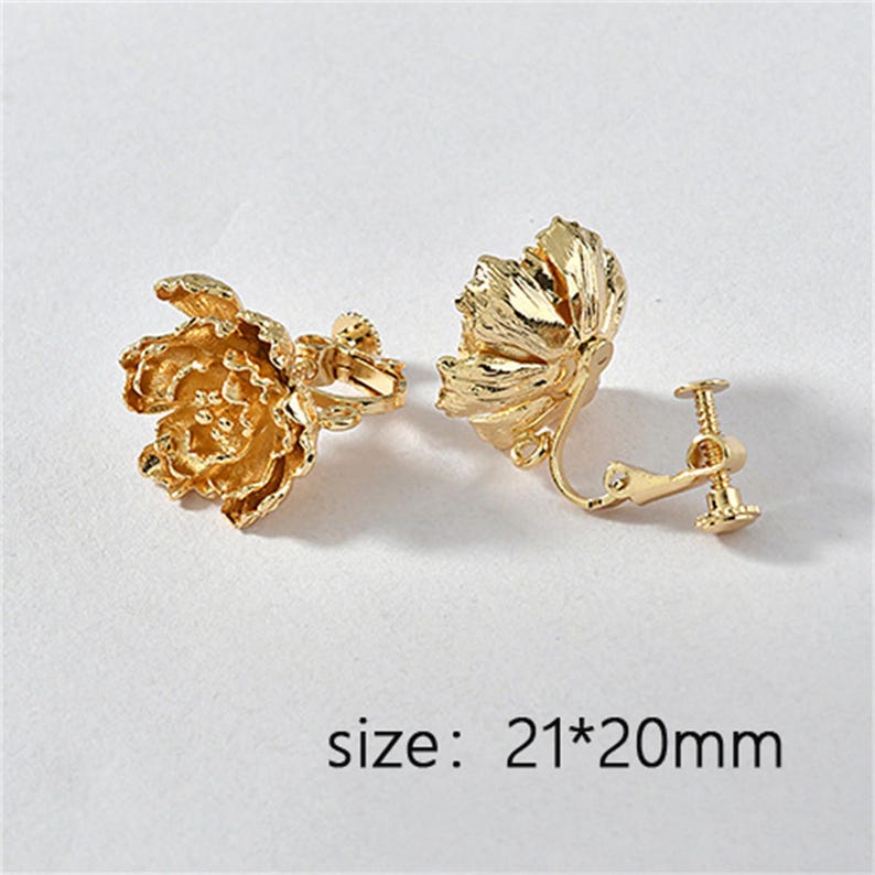 May include: A pair of gold-tone clip-on earrings with a floral design. The earrings are 21mm by 20mm in size.