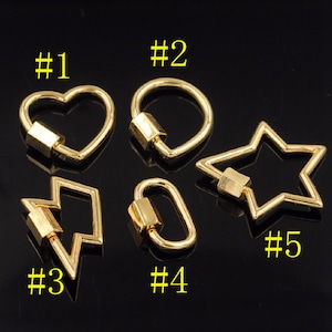 May include: Five gold-toned metal clasps in different shapes: heart, circle, lightning bolt, oval, and star. Each clasp has a small, square-shaped piece in the center.