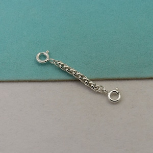 May include: A silver chain extender with two jump rings. The chain is a braided design.
