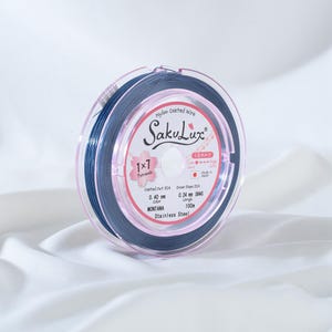 May include: A spool of SakuLux nylon-coated wire in a clear plastic case. The wire is a deep blue color, labeled as Montana, with a diameter of 0.40 mm and a length of 100 m. The case also indicates the wire is 1x7 strands.