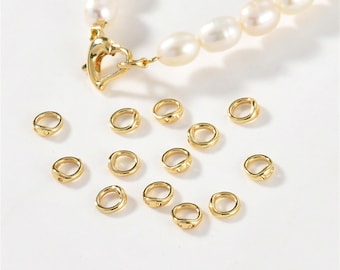 May include: A pearl necklace with a gold heart-shaped clasp and several small gold rings. The pearls are white and oval-shaped. The gold rings are small and have a textured surface.