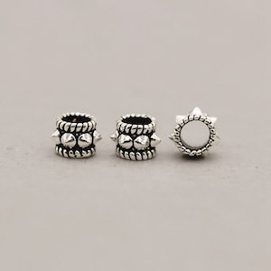 May include: Three silver-toned metal beads with a spiked design. The beads have a textured surface and are round in shape.