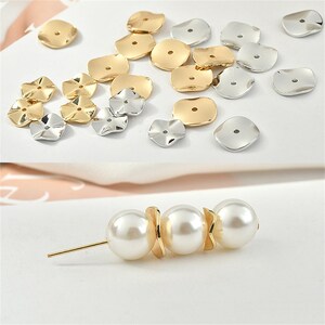 May include: A selection of jewellery components, including gold and silver petal-shaped beads and a pearl and gold pin. The beads have a small central hole. The pin features three large, round pearls and gold accents.
