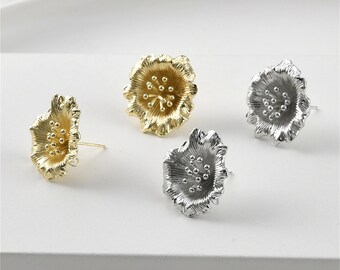 May include: Three pairs of flower-shaped earrings in gold and silver. The earrings are made of metal and have a textured surface.
