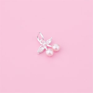 May include: Silver charm featuring two white pearl cherries with a clear crystal leaf design.