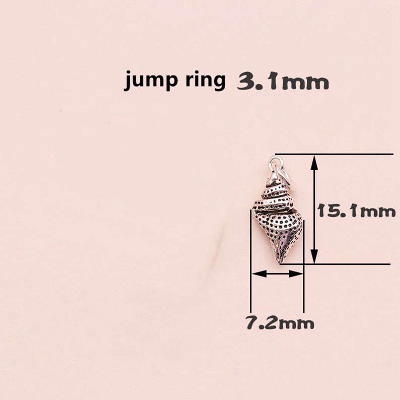 K&ouml;nnte beinhalten: Silberner Muschel-Anh&auml;nger mit einem Sprungring. Der Anh&auml;nger ist 15,1 mm hoch und 7,2 mm breit.