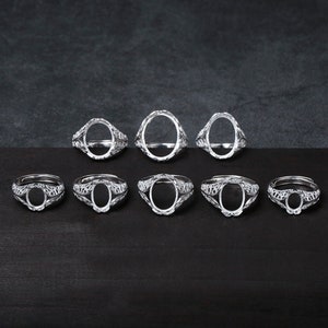 Könnte beinhalten: Acht silberne Ringe mit ovalen Fassungen. Die Ringe haben ein zartes, filigranes Design.