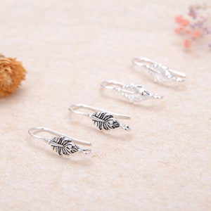 May include: Four silver earring hooks with a leaf design. The hooks are arranged in a row, with the largest hook at the bottom and the smallest hook at the top.