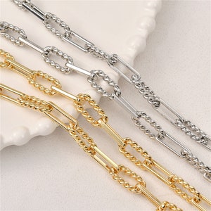 May include: Three gold, silver, and white chain necklaces with a rope-like design. The chains are made of linked oval shapes.