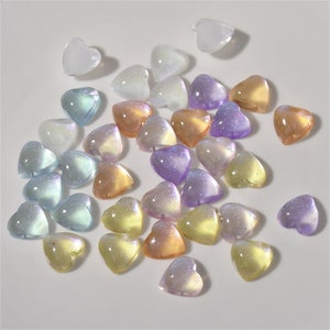May include: Assortment of iridescent heart-shaped beads in various pastel colors, including pink, purple, blue, and yellow.